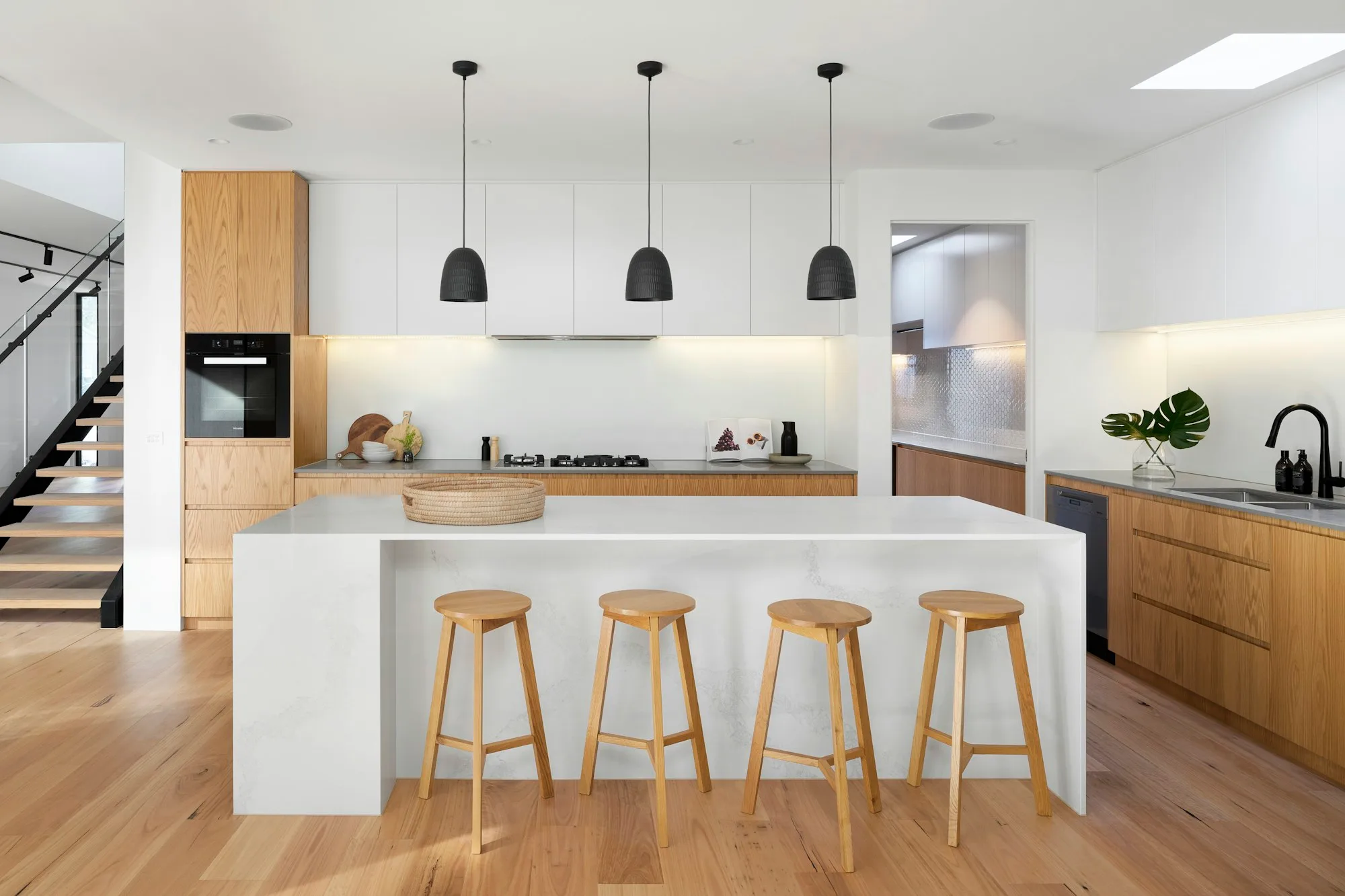 Remodeled kitchen with white oak cabinets, quartz island and pendant lights